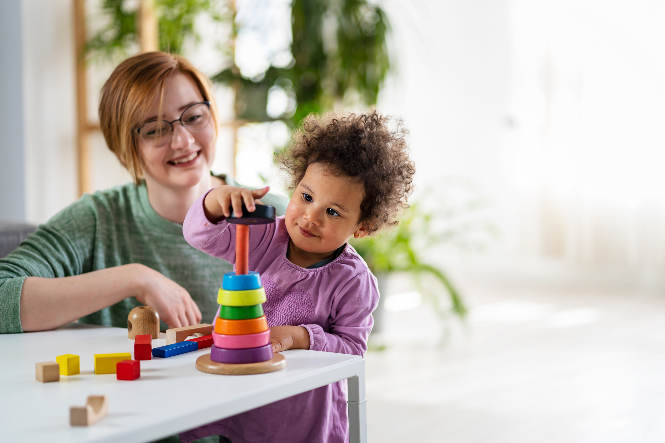 ABA therapist working with a young child using colorful stacking toys at a Behavioral Innovations Maryland center