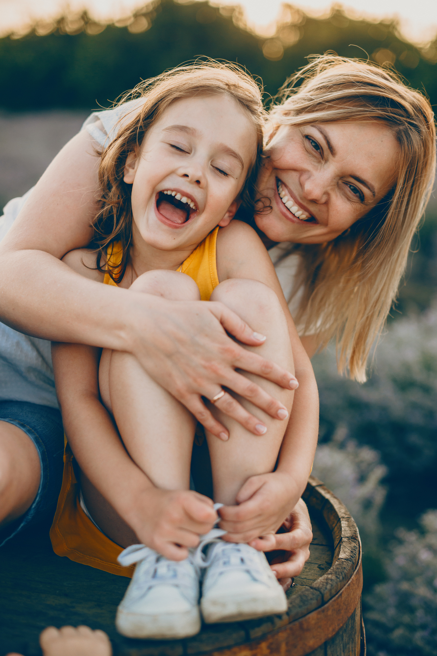 Mother hugging and laughing with her young daughter outdoors