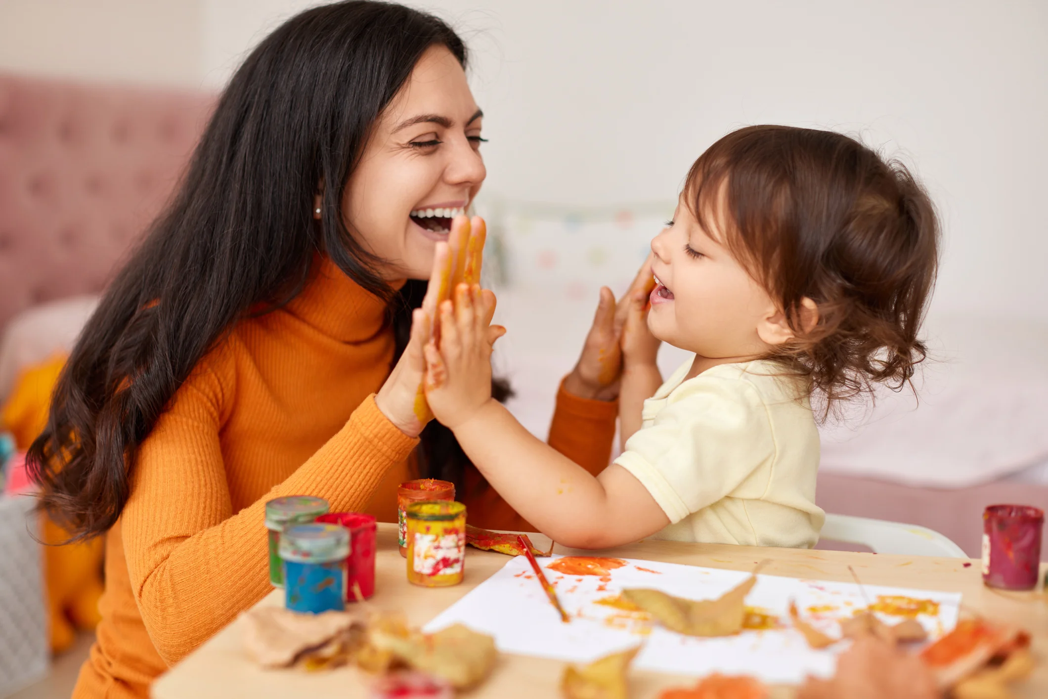 Therapist and toddler laughing together during a finger painting activity