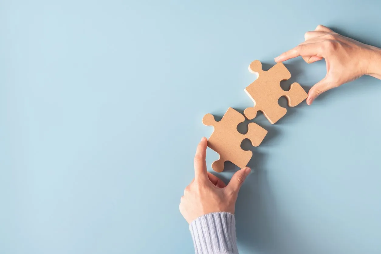 Two hands holding jigsaw, Concept for teamwork Building a success.