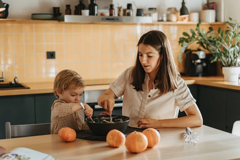 a woman and child are preparing food in a kitchen