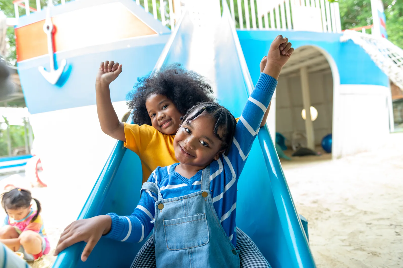 Un niño y una niña africanos se deslizan y juegan juntos en el parque infantil del parque
