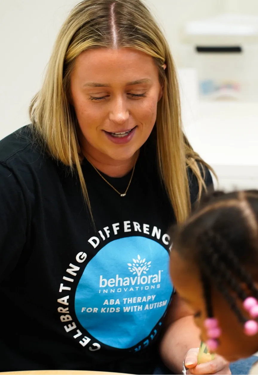 a woman wearing a behavioral innovations shirt talks to a child
