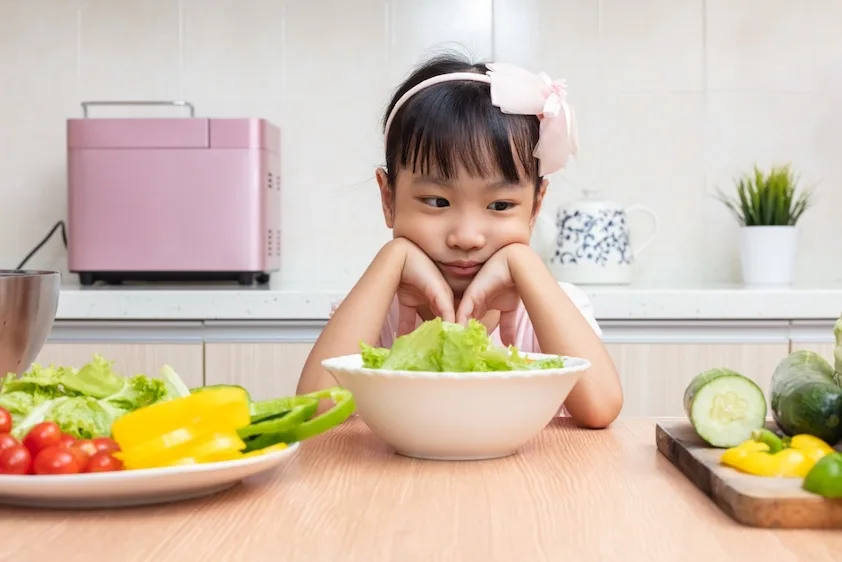 young girl staring at vegetables
