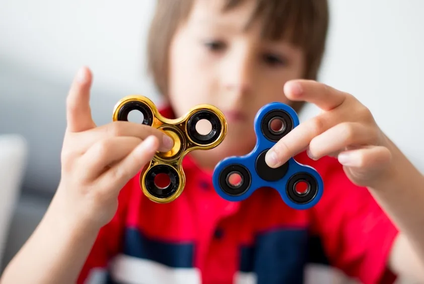 young boy playing with fidget spinners 