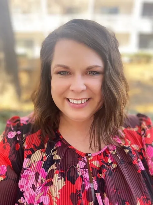 a woman wearing a red and pink floral shirt is smiling for the camera