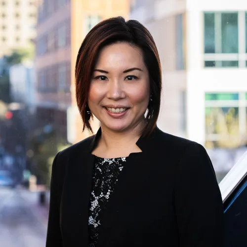 a woman in a black jacket smiles for the camera
