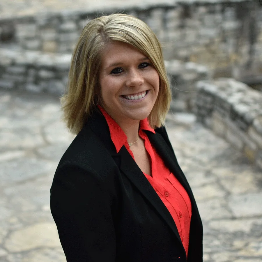 a woman in a black jacket and red shirt smiles for the camera