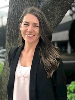 a woman is standing in front of a tree and smiling for the camera