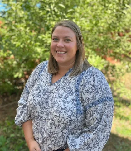 a woman wearing a blue and white floral shirt smiles for the camera