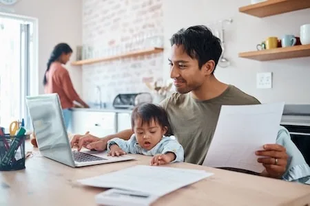 Padre trabajando con su hija en el regazo
