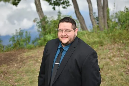 a man in a suit and tie is standing in a field