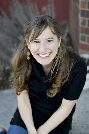a woman wearing a black shirt and earrings is smiling for the camera