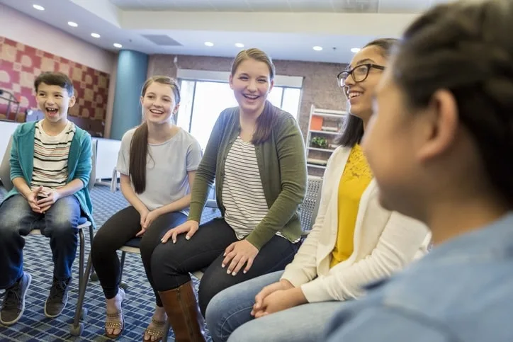 a group of children are sitting in a circle and laughing