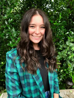 a woman wearing a green plaid jacket smiles for the camera