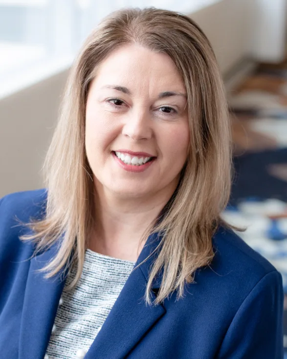 a woman in a blue jacket smiles for the camera