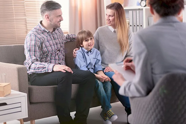 a family sits on a couch talking to a doctor
