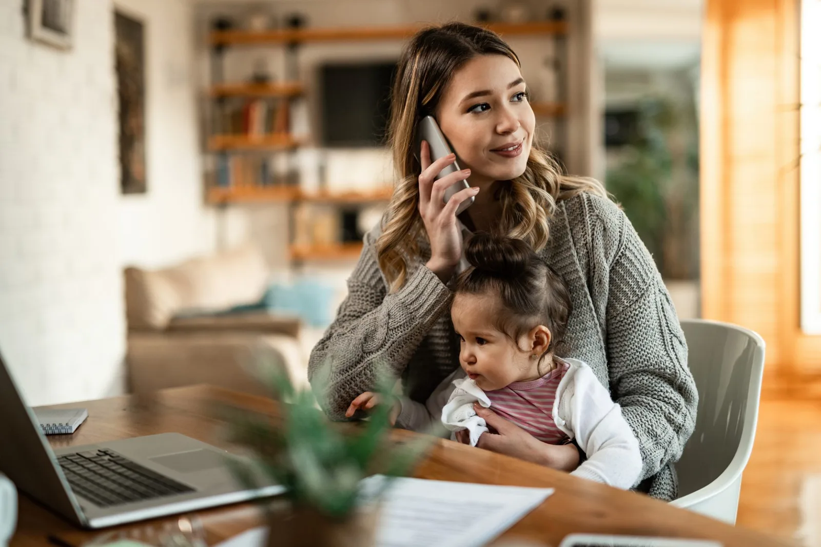 Mother on the phone with daughter in lap