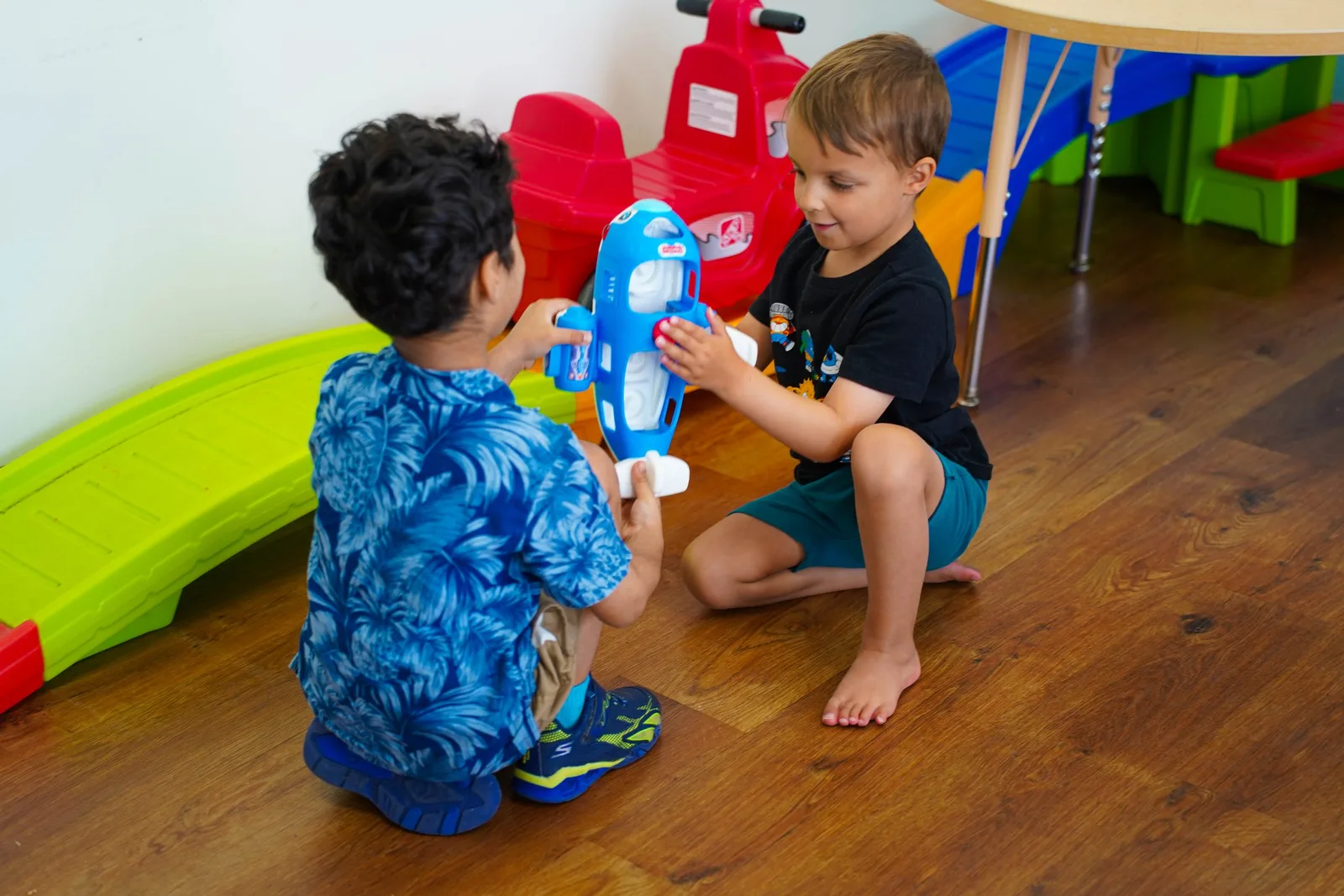 two young boys are playing with a toy airplane on the floor