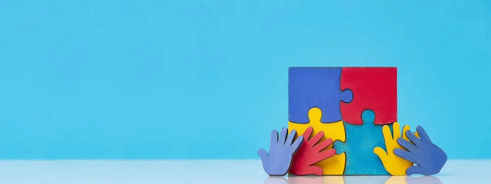Colorful puzzles hands on blue background. World Autism Awareness Day Concept