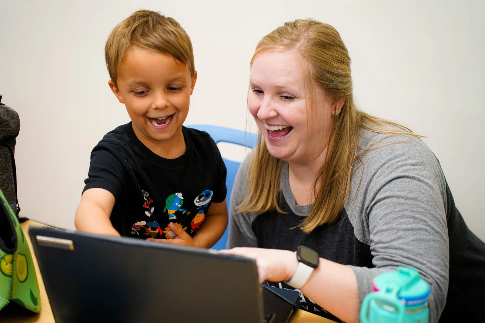 therapist and child laughing while looking at computer