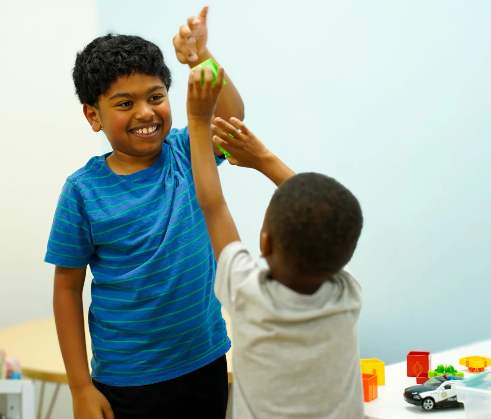 Dos niños pequeños están jugando con juguetes y se dan un choque de manos.