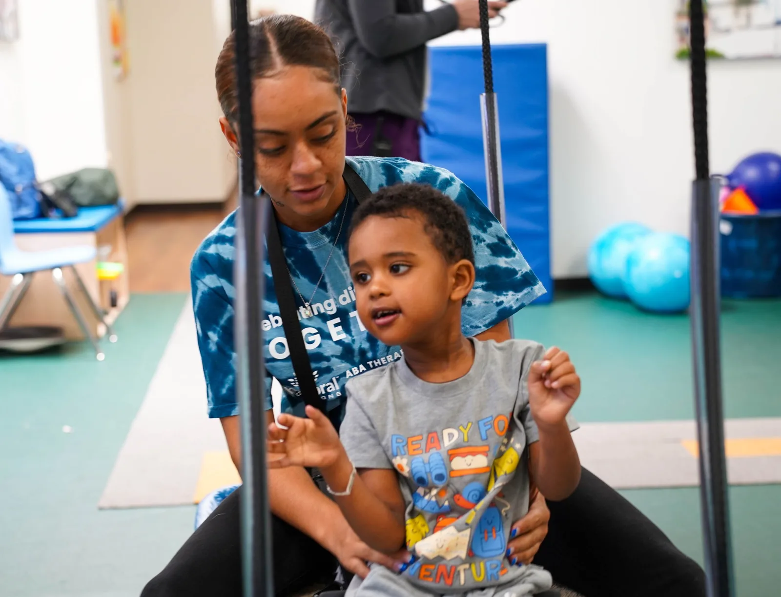 therapist supporting a young boy bouncing on a yoga ball