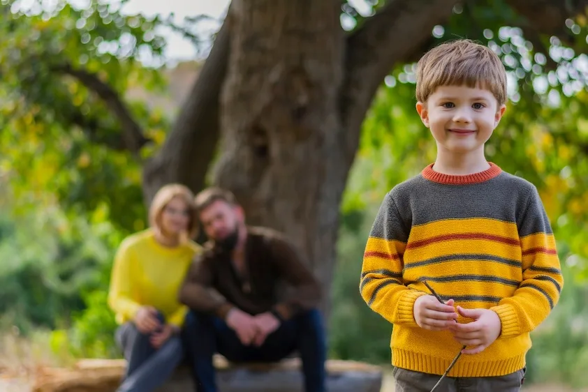 child playing outside with parents supervising in the back