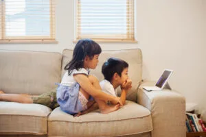 Un niño y una niña tumbados en un sofá mirando una tableta digital