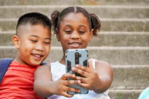 Primer plano de niños multiétnicos felices usando el móvil para hacer vlogging