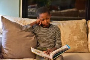 little boy sitting on the couch reading a book