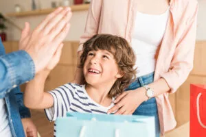 happy boy with shopping bags giving high five to father