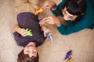 una madre y su hijo jugando con dinosaurios de juguete
