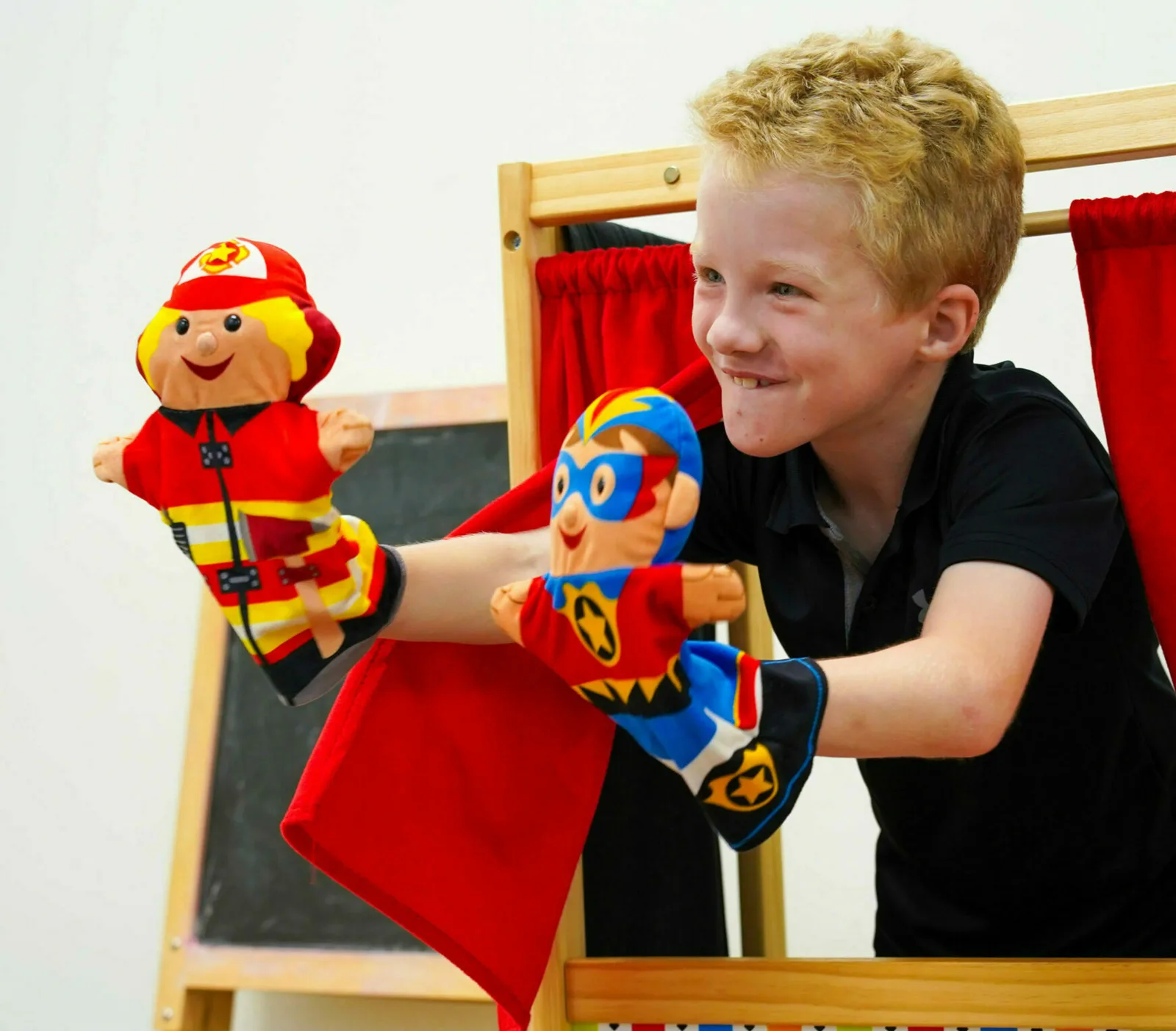 Un niño está jugando con una marioneta de bombero y otra de superhéroe.
