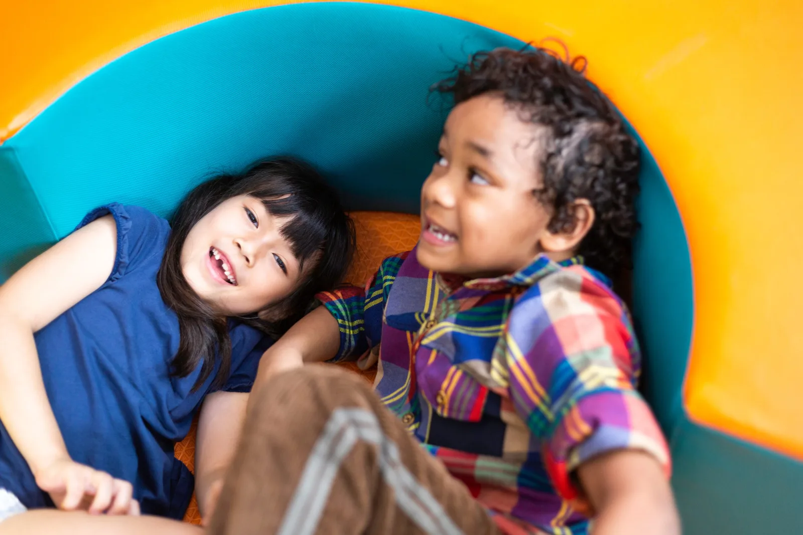 a boy and a girl are playing on a slide together