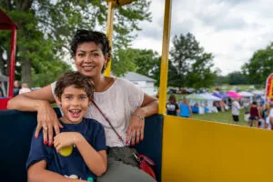 A cute young boy with a silly smile playfully poses for a picture with his mother