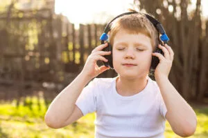 boy with headphones relaxing listening to music sitting on the grass in nature