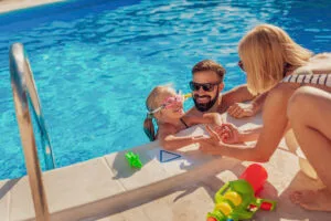 Parents teaching their daughter to swim in the pool on summer vacation