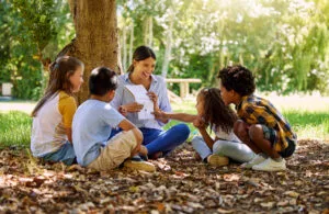 teacher reading a book to her in a park