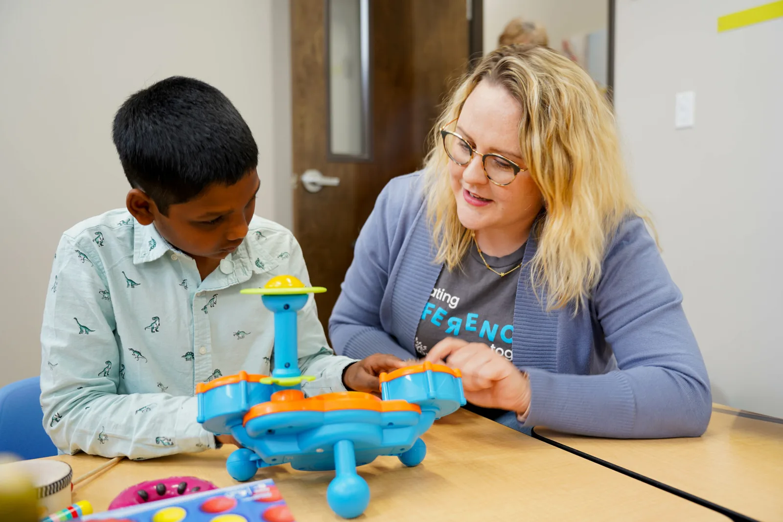 a woman wearing a t-shirt that says ' making ference ' is playing with a child