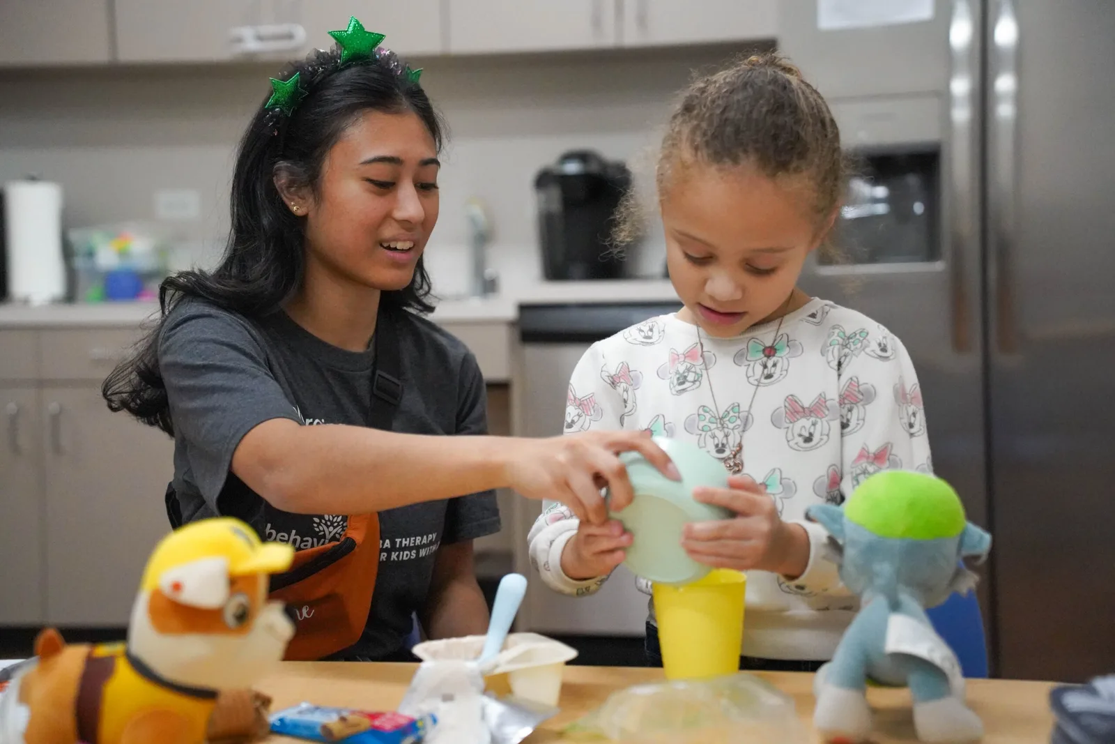a woman and a little girl are sitting at a table playing with stuffed animals