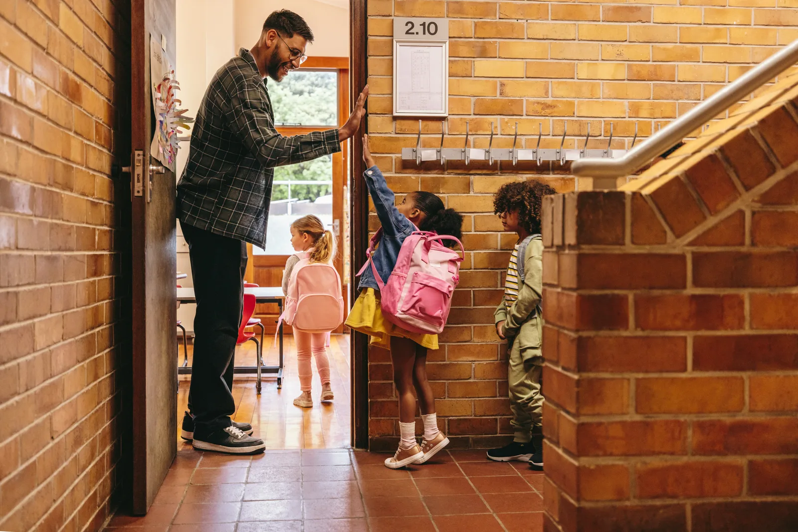 Teacher greeting students in a school hallway
