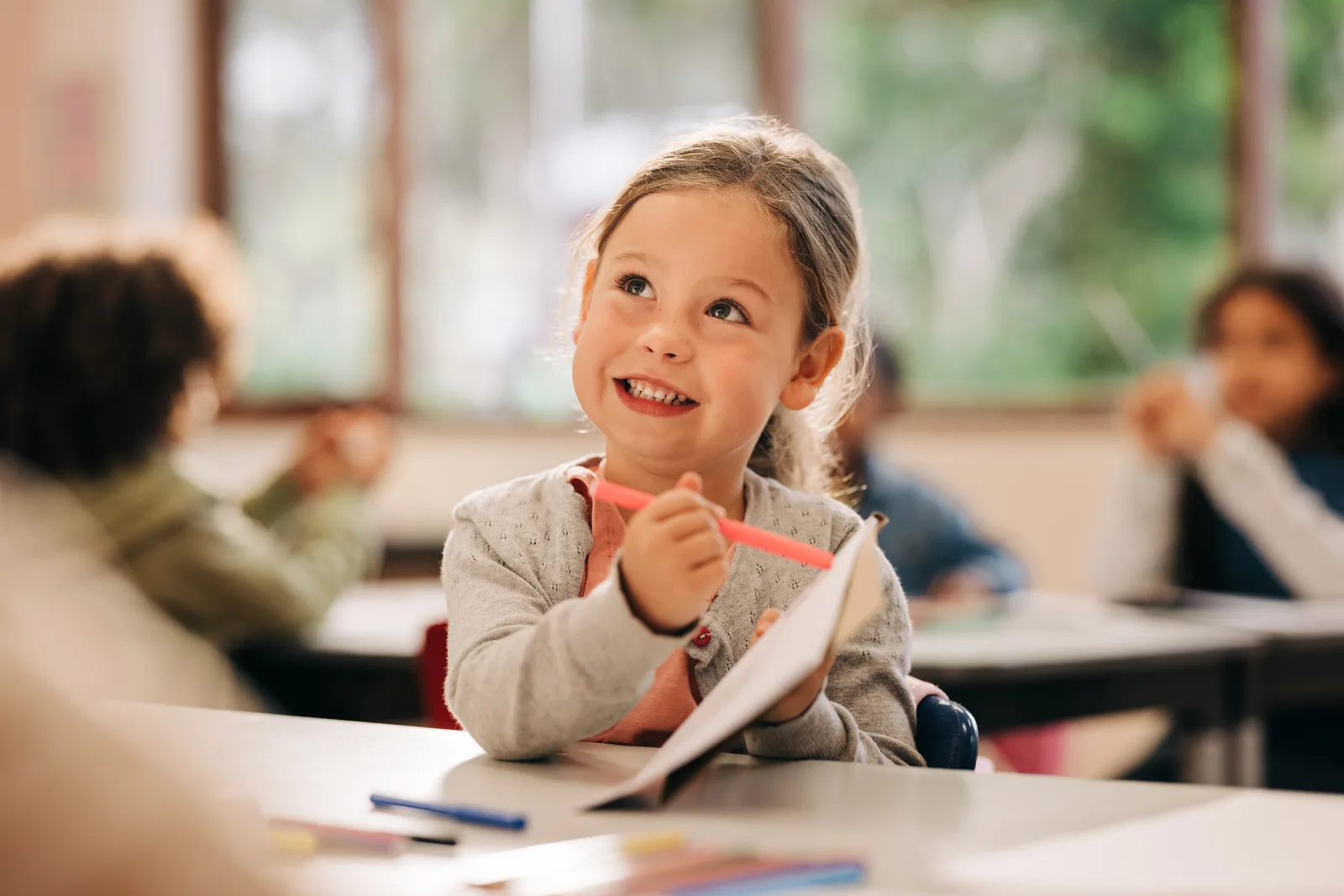 Young student smiling while working at a classroom desk