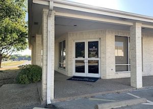 a white brick building with a porch and two doors