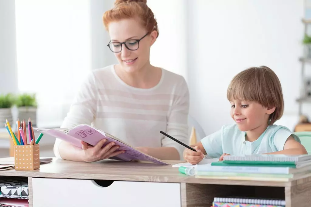 a woman is helping a young boy with his homework