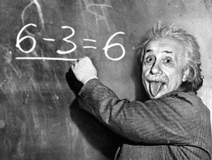 albert einstein is sticking out his tongue while writing on a blackboard