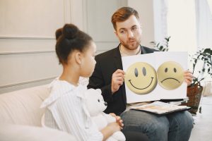 a man is holding a picture of a smiley face and a sad face