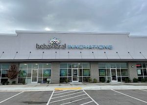 the front of a behavioral innovations building with a parking lot in front of it