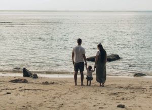 a family standing on a beach looking at the ocean