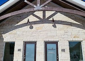 the front of a brick building with a wooden roof and a glass door